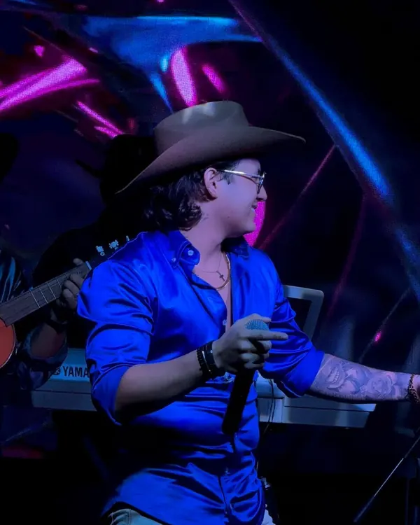 Ricardo en tarima con camisa azul y su banda detrás