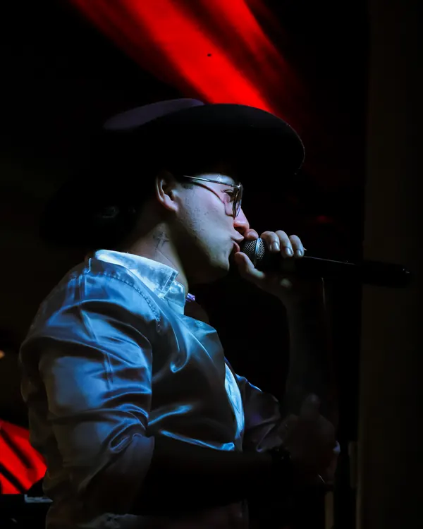 Ricardo cantando con el micrófono en tarima